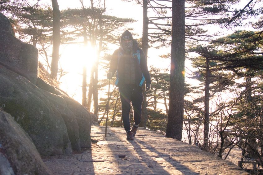man hiking in huangshan with the sunrising behind
