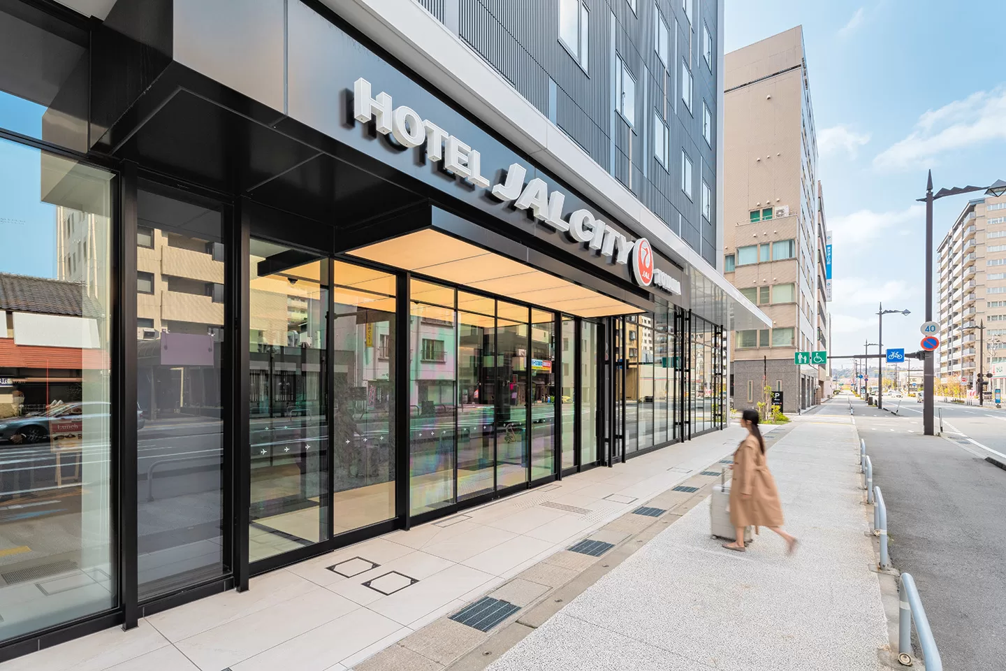 Girl entering Hotel JAL City Toyama Entrance with suitcase